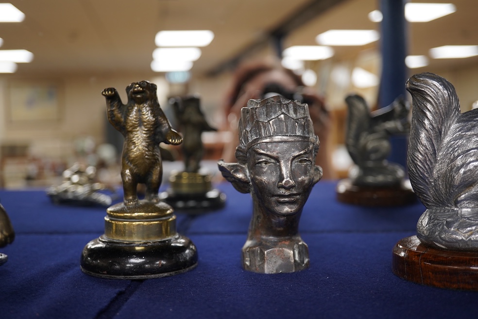 Seven chrome, brass and aluminium car mascots, etc. including an unusual and comical aluminium car mascot in the form of a squirrel holding a nut, together with a standing bear, an Art Deco winged head, a ram, a running
